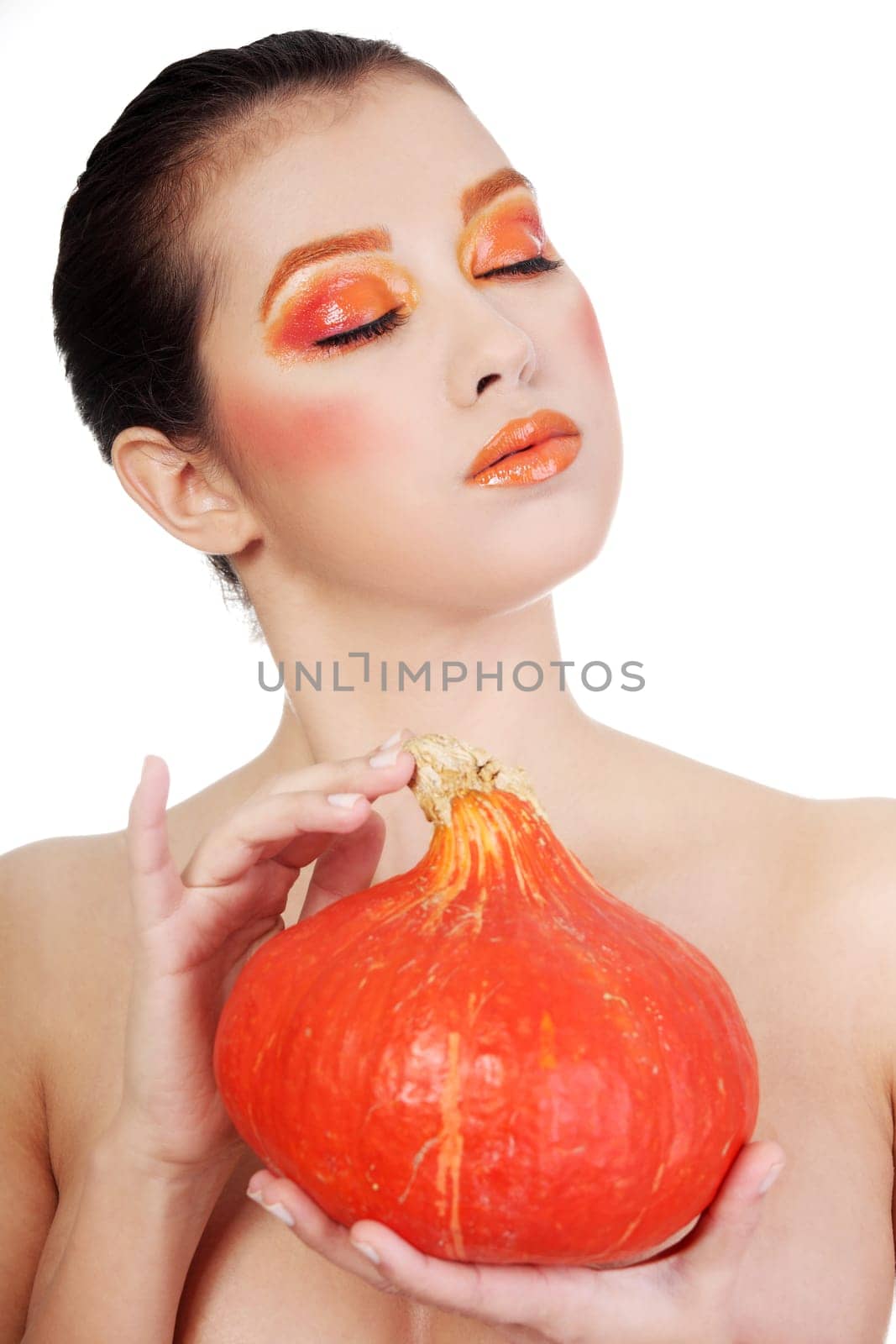 Beautiful woman with orange make up holding pumpkin