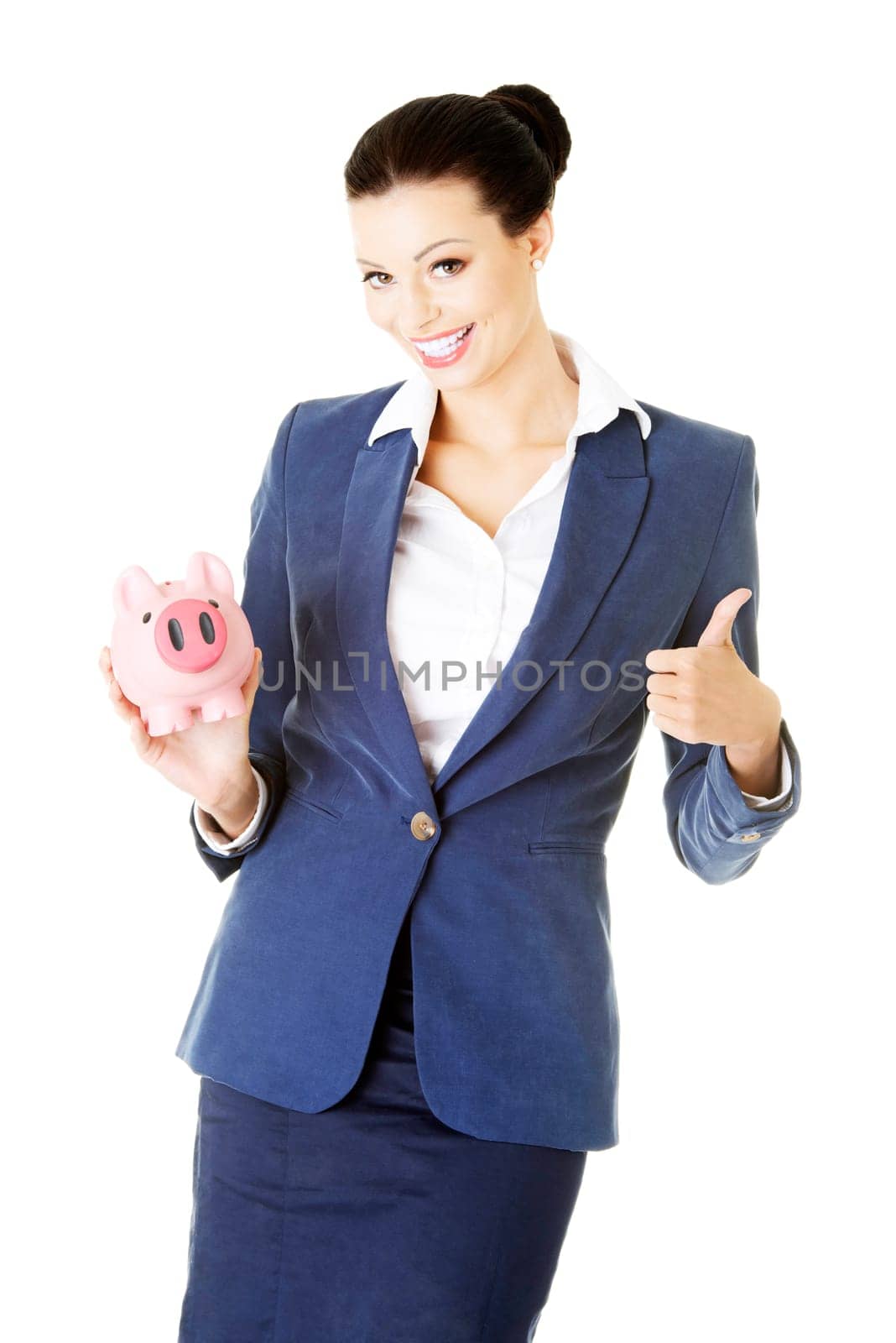 attractive young business woman holding piggy bank and showing ok. isolated on white.