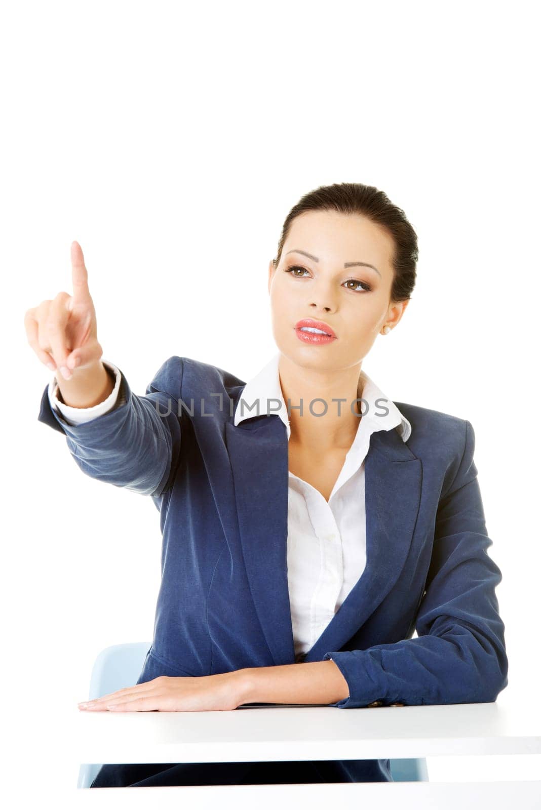 attractive woman sitting and pointing up. isolated on white.