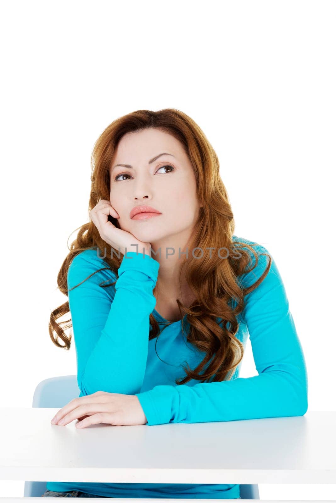 attractive casual woman proping her head and looking up. isolated on white.