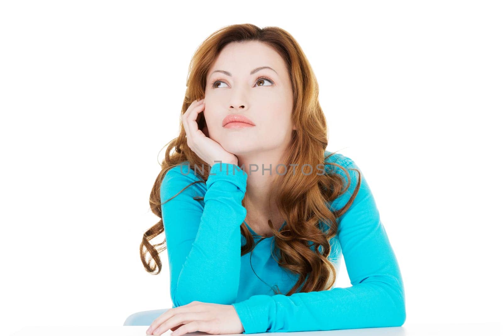 attractive casual woman proping her head and looking up. isolated on white.