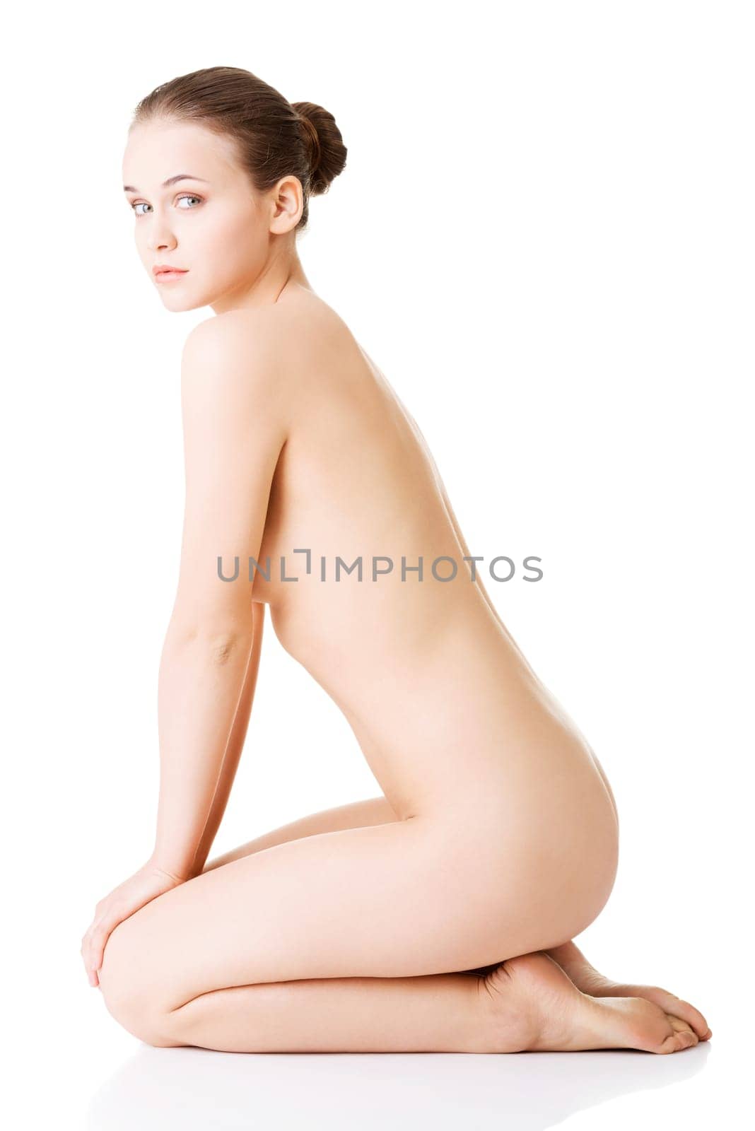 attractive naked woman in a crouch. isolated on white. side view.