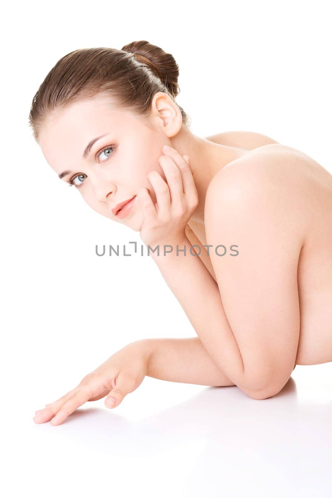 attractive naked woman proping her head while lying on the floor. looking at camera. isolated on white.