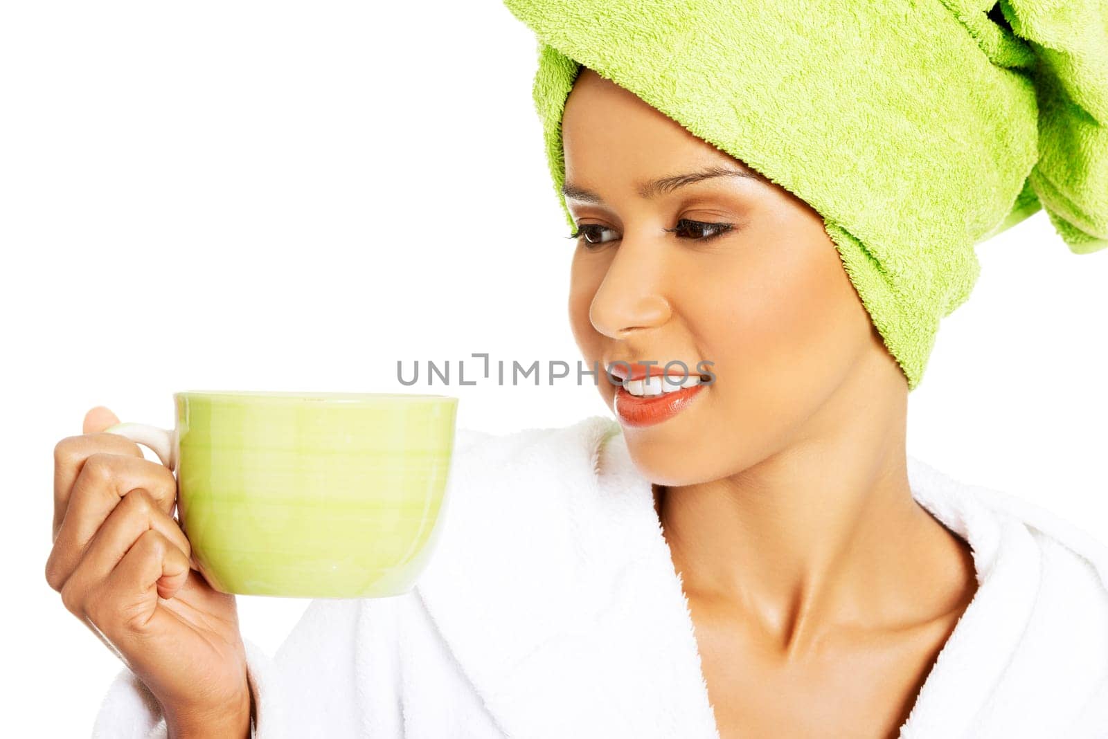 attractive woman wrapped in towel on head with a turban,holding a cup. isolated on white.