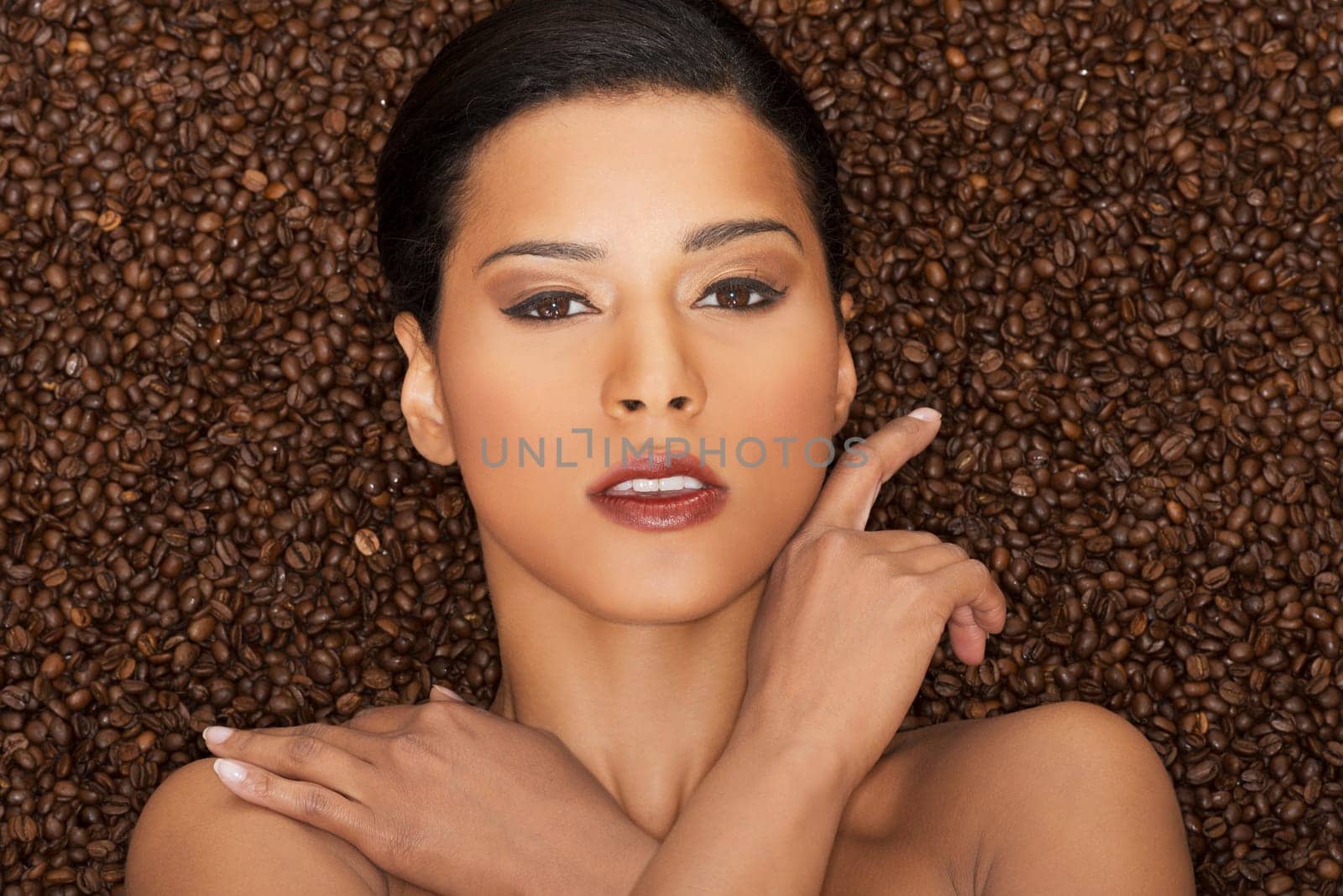 attractive woman lying in coffee grains. fron view. closeup.
