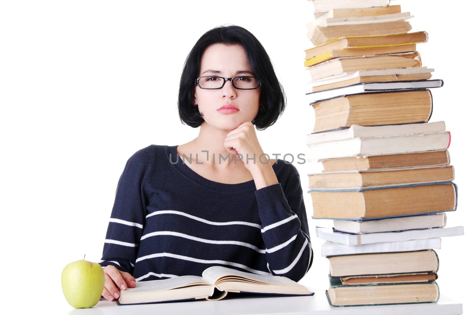 arrtactive young woman sitting next to stack of book with an apple. isolated on white.