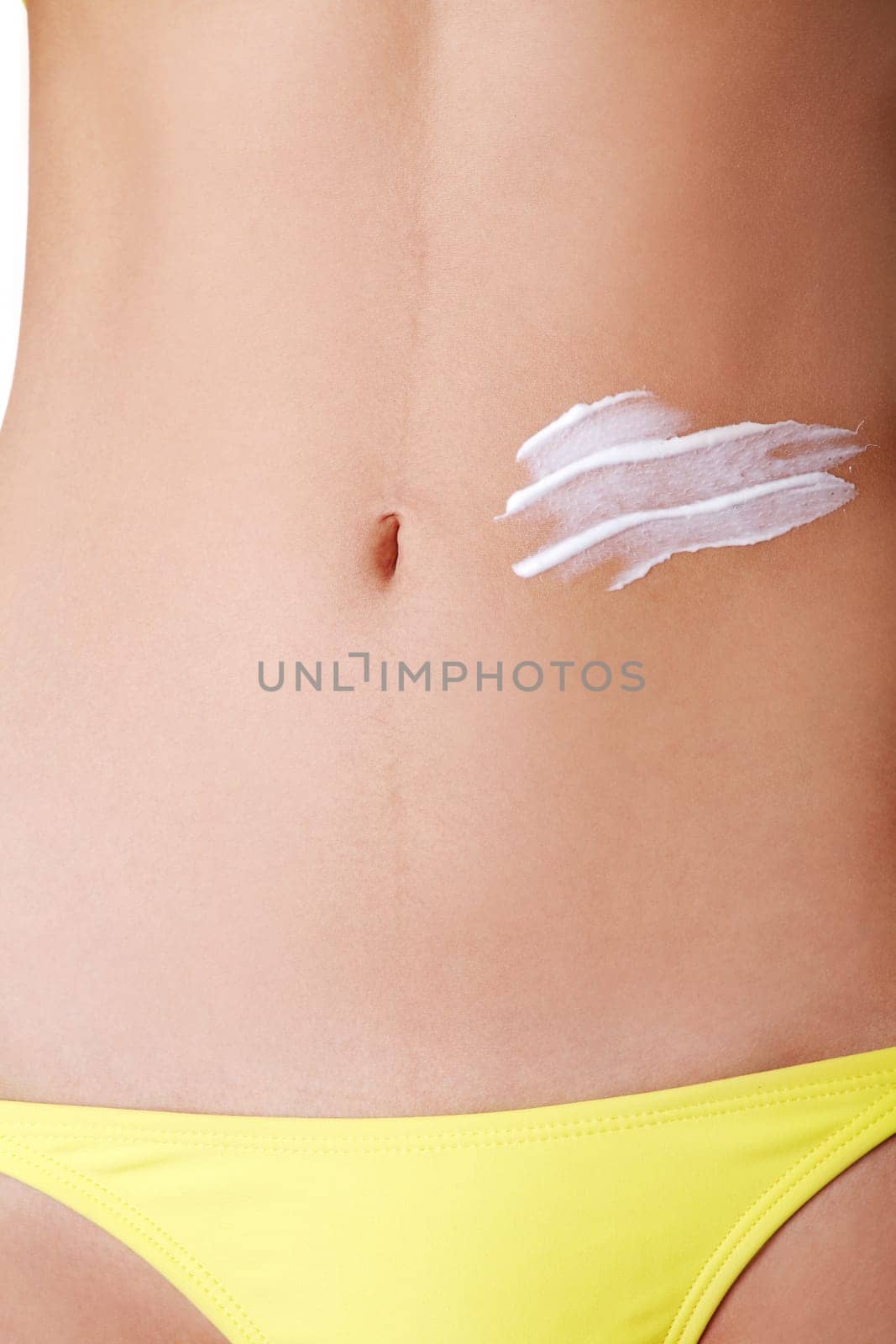 slim sexy female's belly with lotion body. closeup. isolated on white.