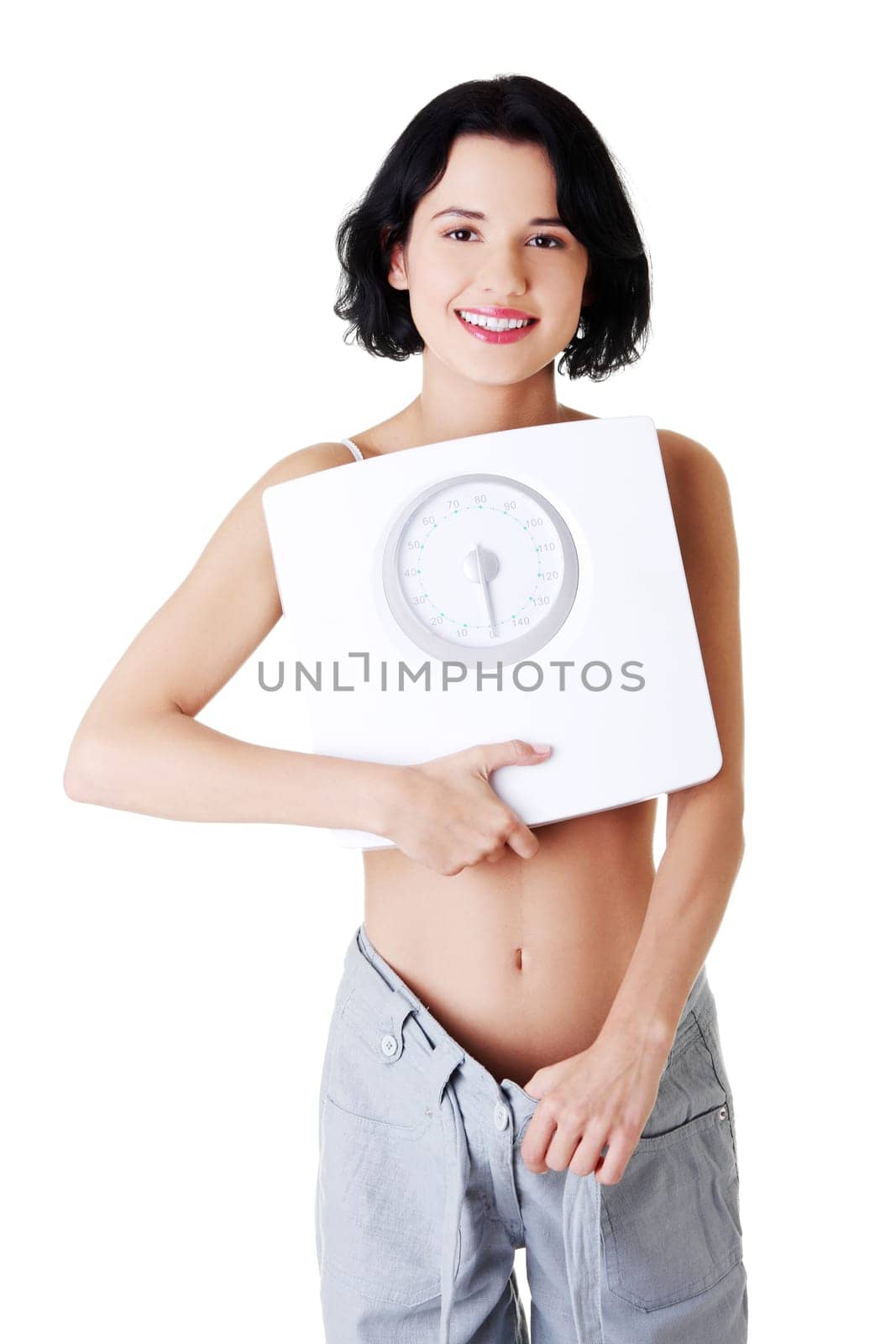 attractive woman in baggy trousers with scale. isolated on white.