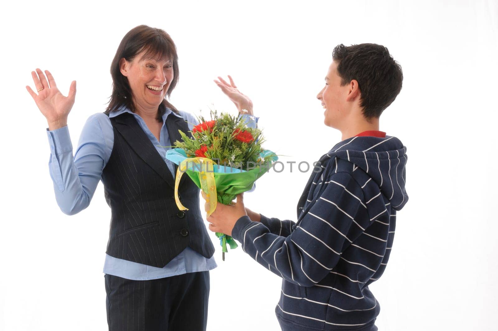 Mother and her teenage son,he presents her with a bouquet of flowers against a white background
