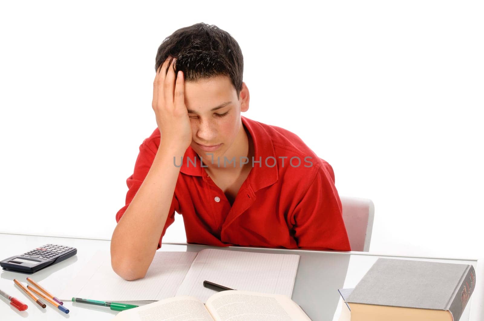 Boy sits exhausted and frustrated about homework at desk in front of a white background