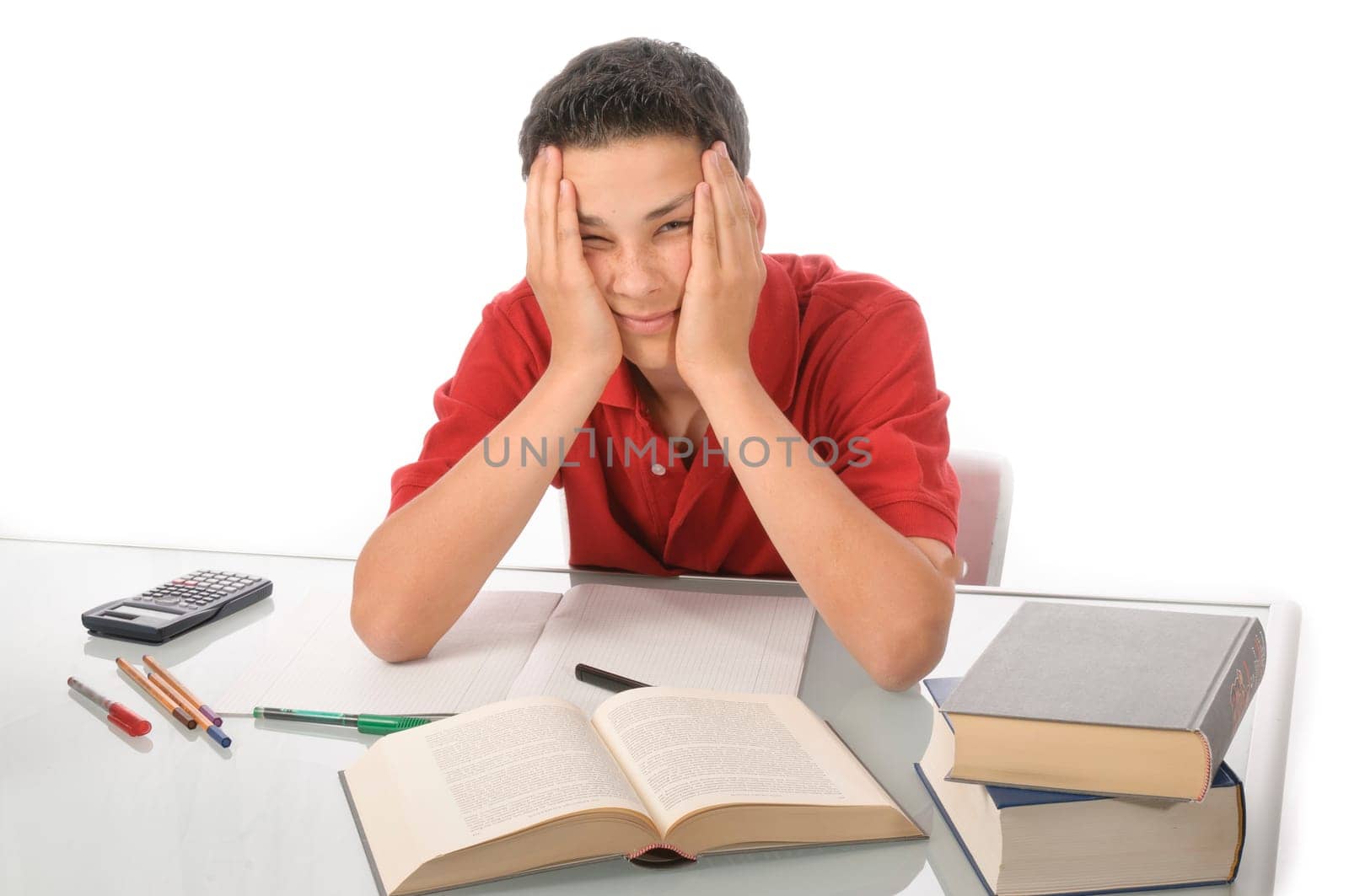 Boy sits exhausted and frustrated about homework at desk in front of a white background