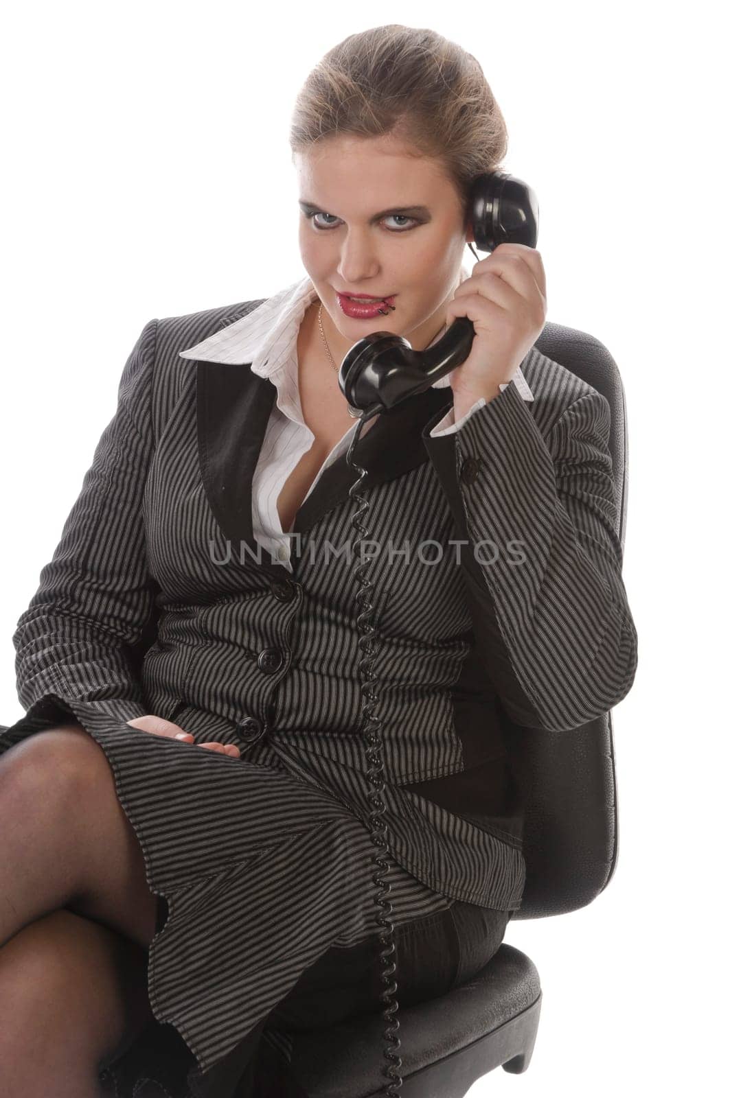 Young woman in grey business suit and high heels making calls with landline telephone against a white background