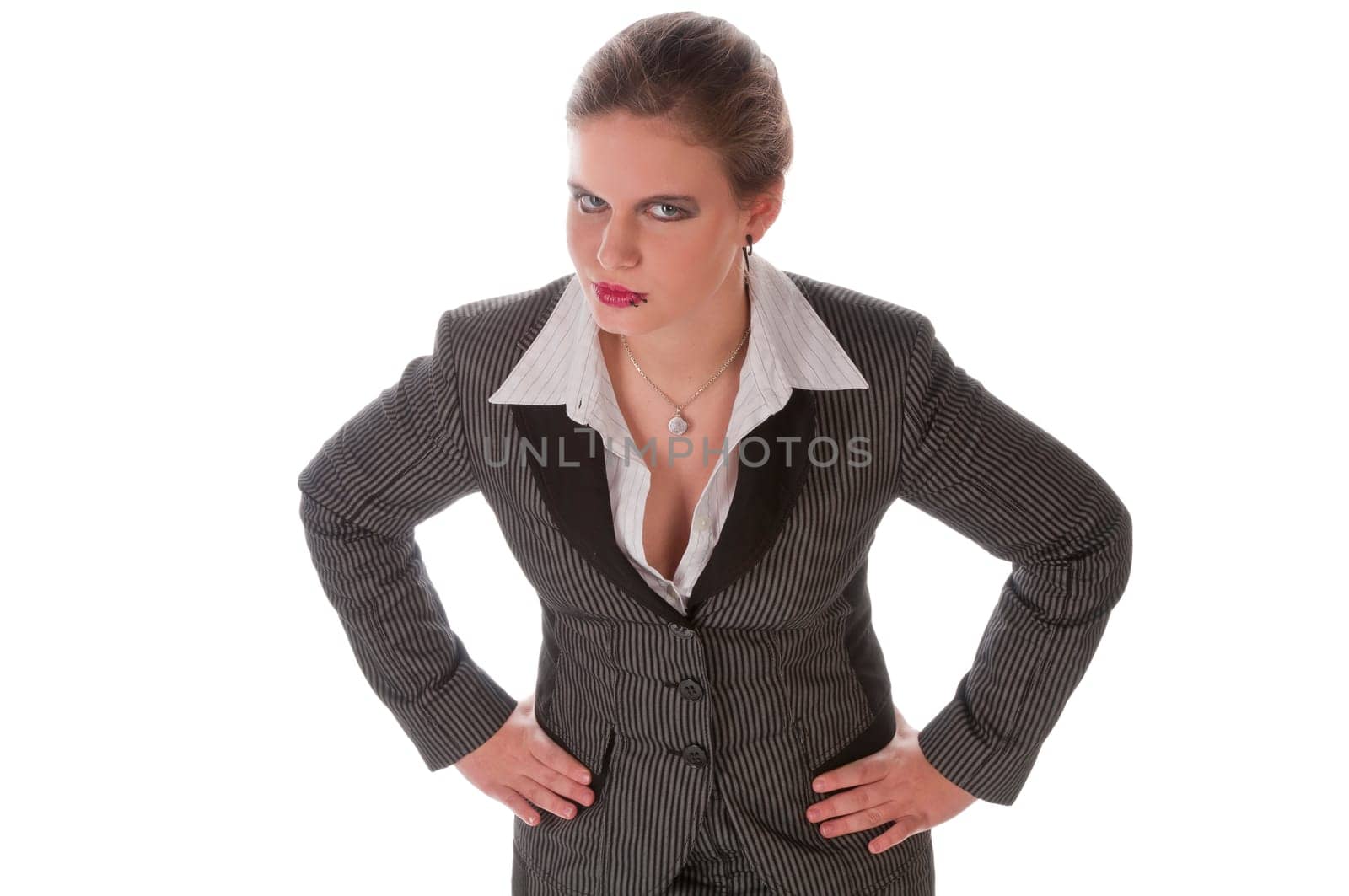 Young woman in grey business suit and high heels poses against a white background