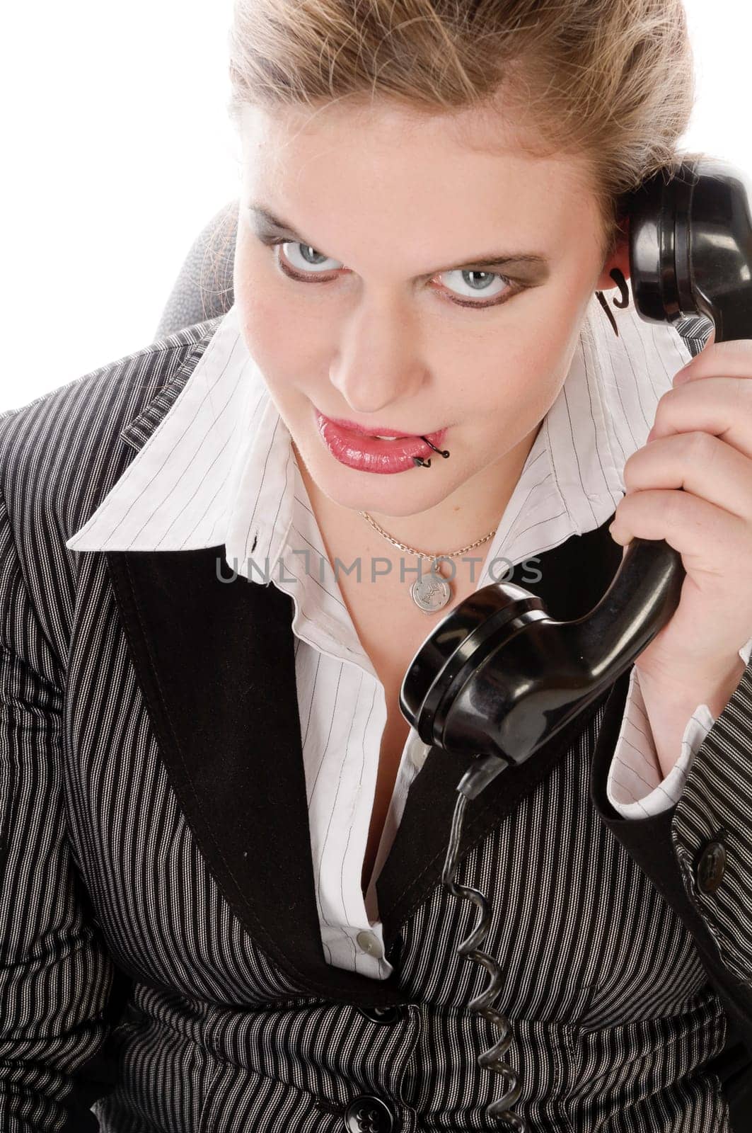 Young woman in grey business suit and high heels making calls with landline telephone against a white background