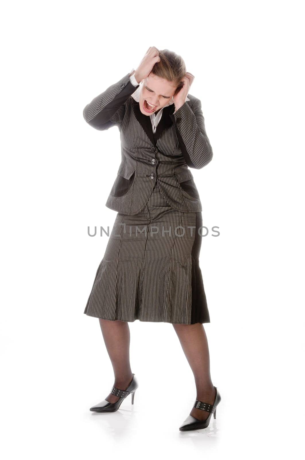 Young woman in grey business suit and high heels is stressed and ruffles her hair against a white background