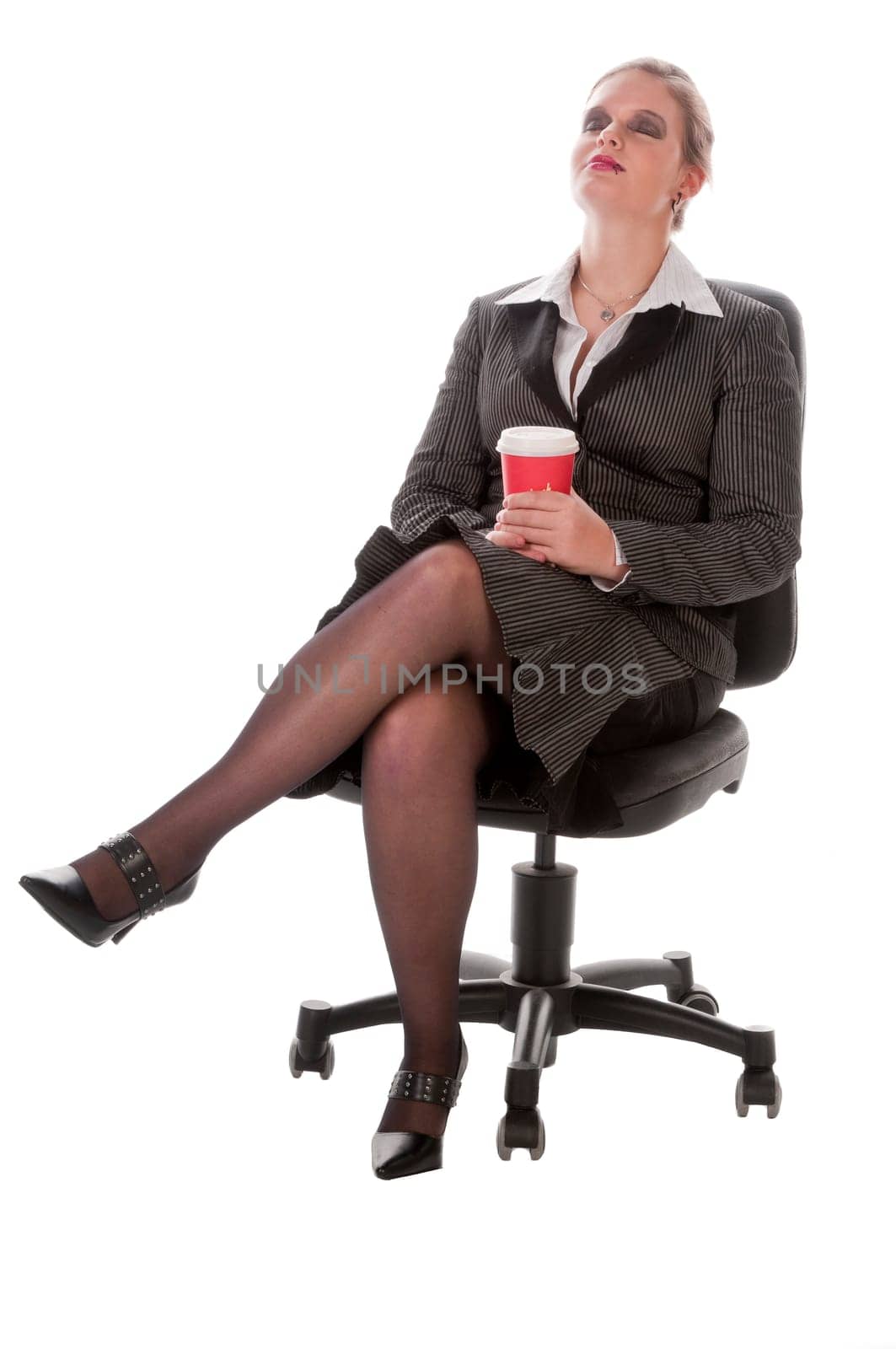 Young woman in grey business suit and high heels poses with coffee-to-go paper cups against a white background