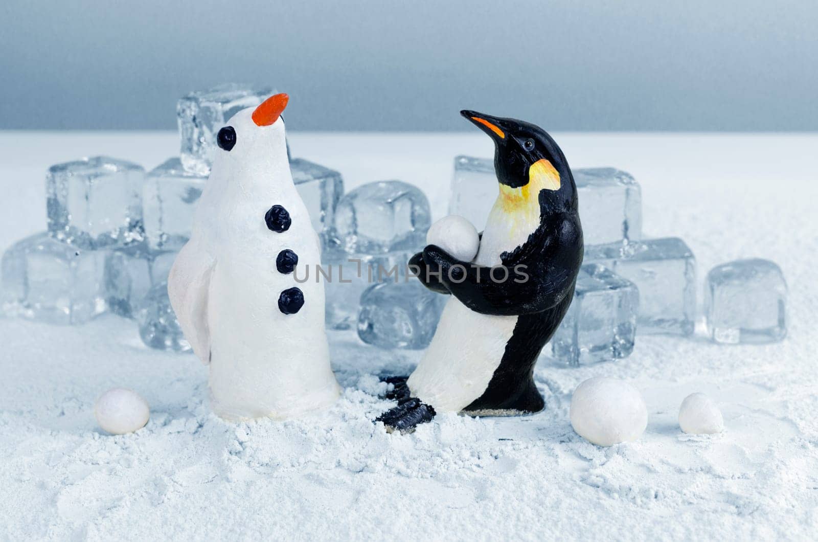 Penguin lifting a snowball to make a snow penguin