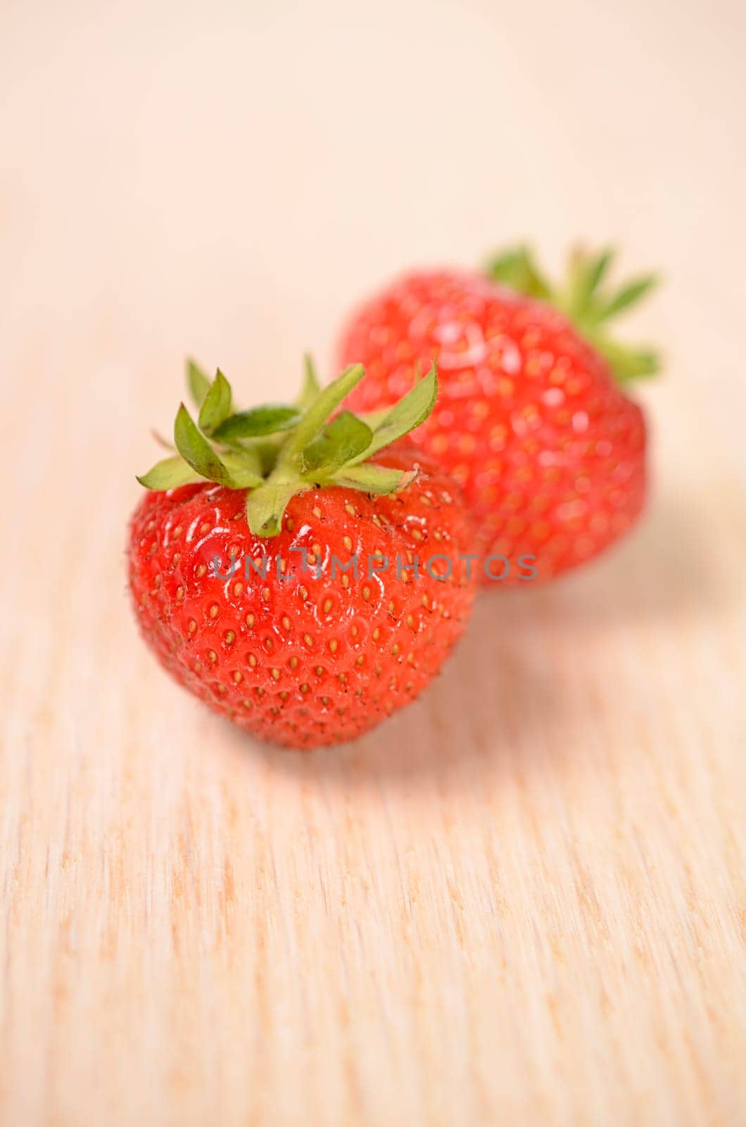 Two fresh strawberries on a wooden background