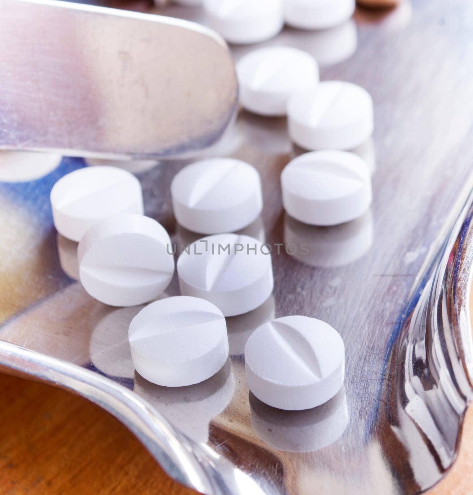 Close-up of two white medical pills on stainless steel tray.