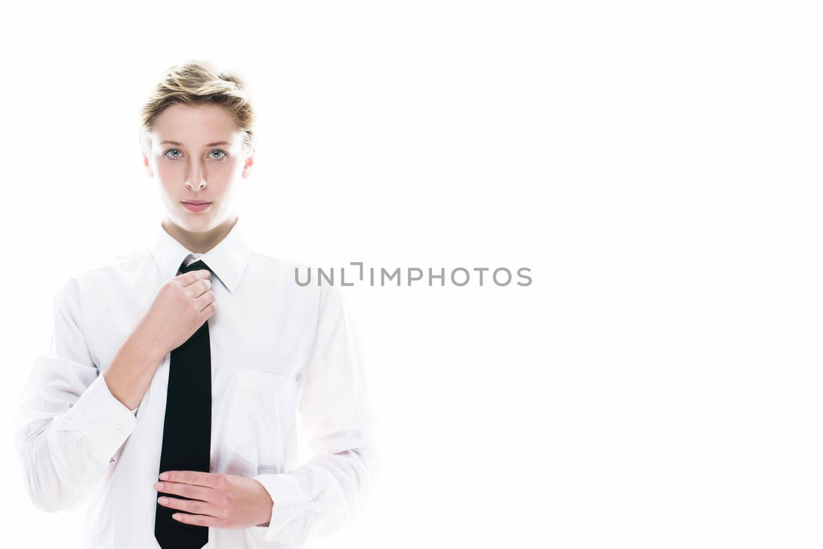 Young androgynous woman straightens her tie on a white background