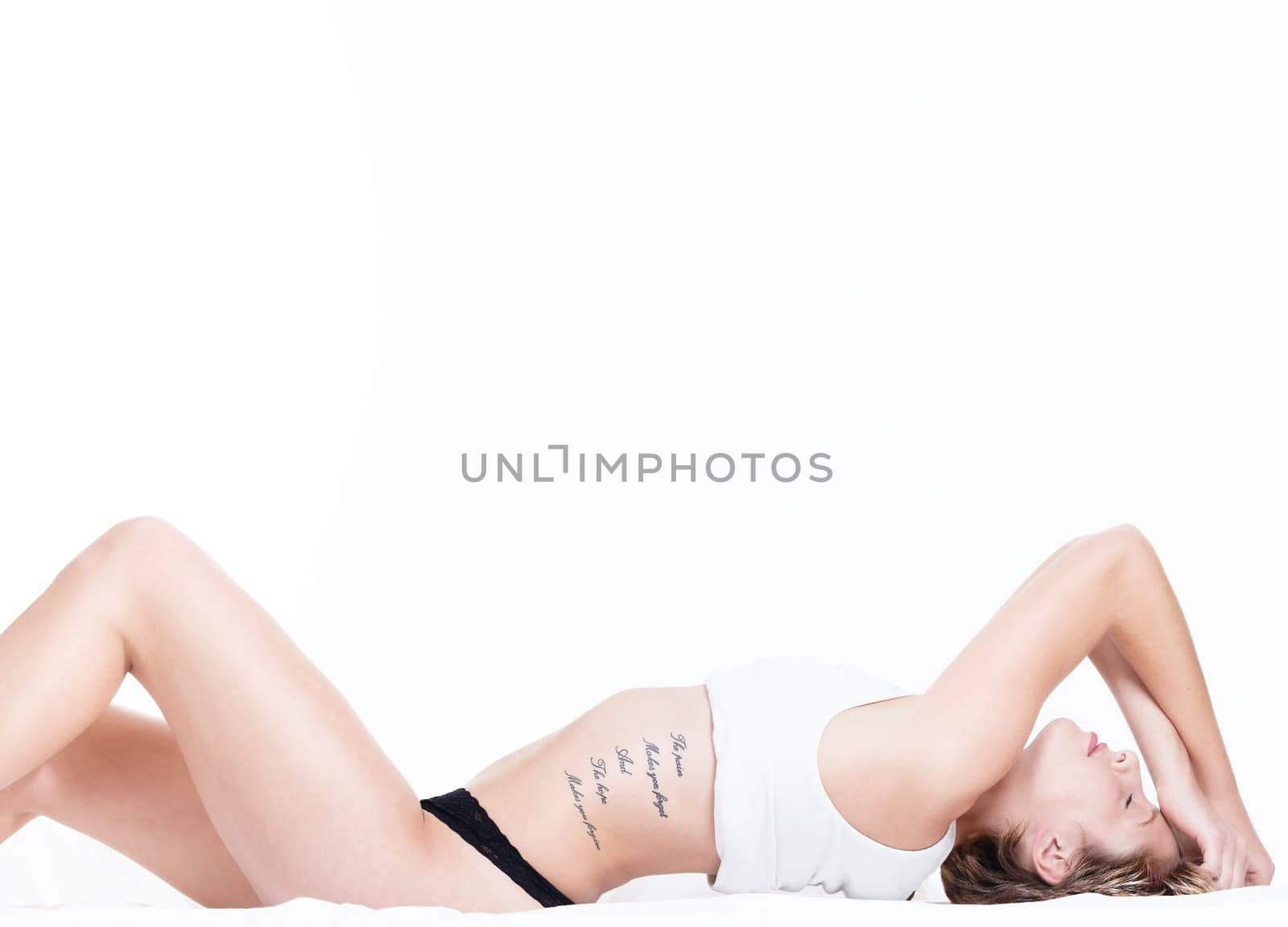 Sensual young blonde woman on the bed on a white background