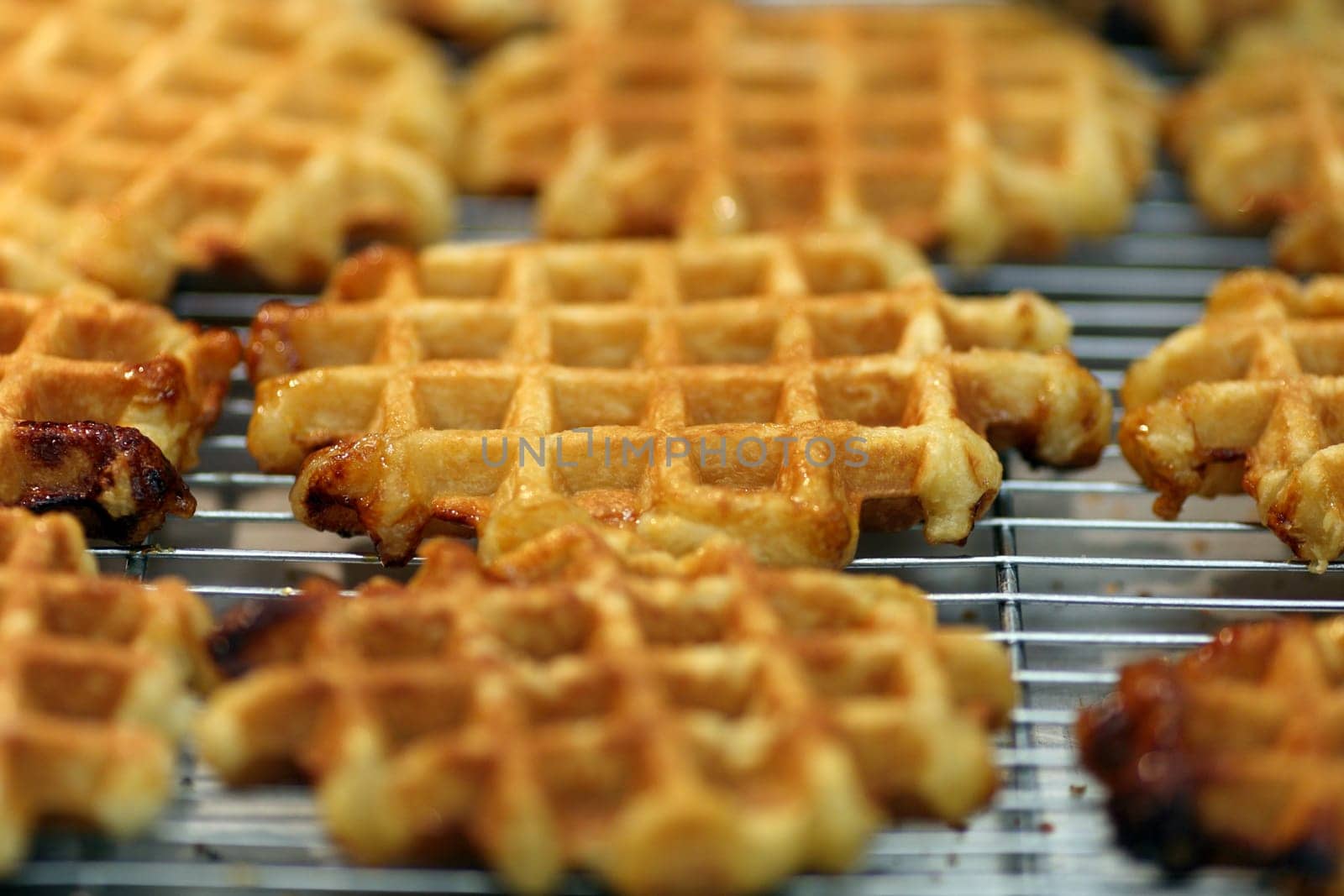 Details of many golden waffles on a grill.