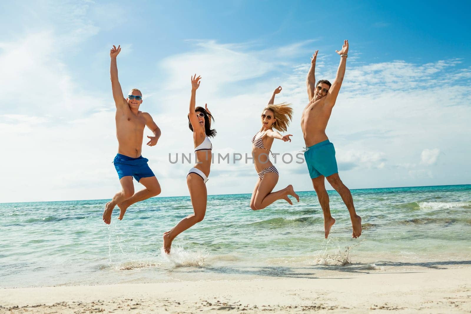 Group of laughing young people on the beach in summer holiday leisure lifestyle