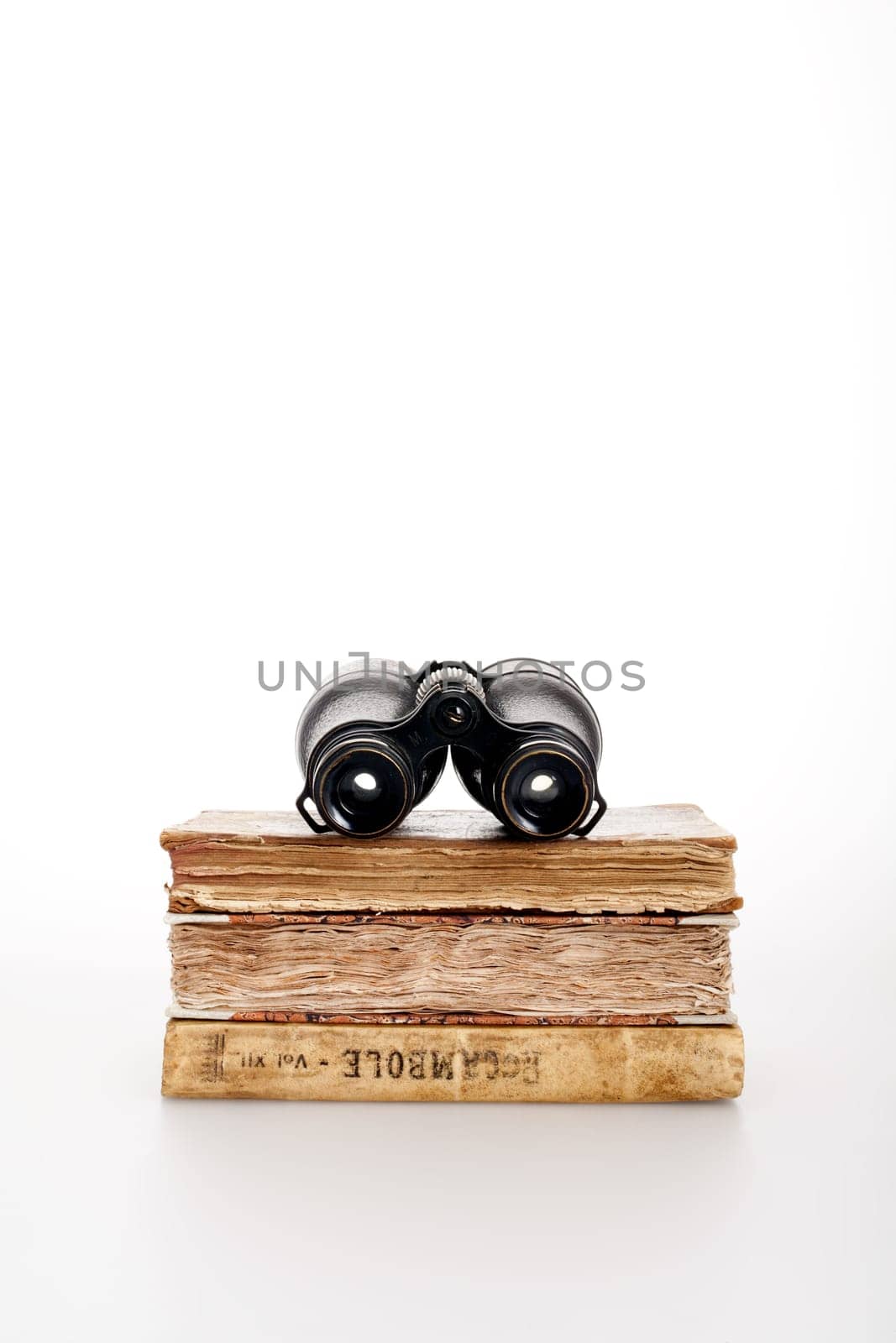 Antique books and binoculars symbolizing adventure and travel book, on a white background