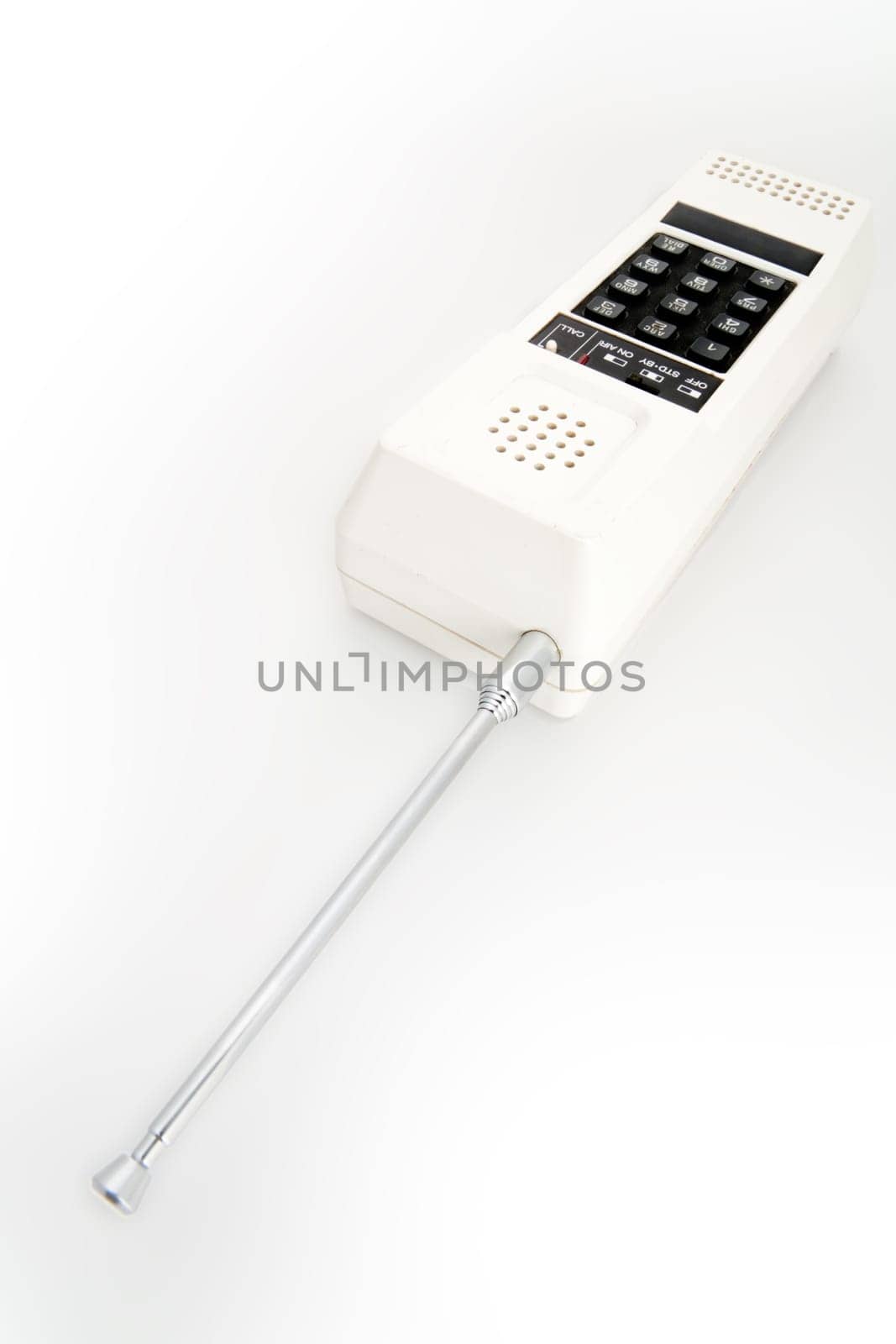 A white cordless telephone from the eigthes with black buttons and a telescopic antenna