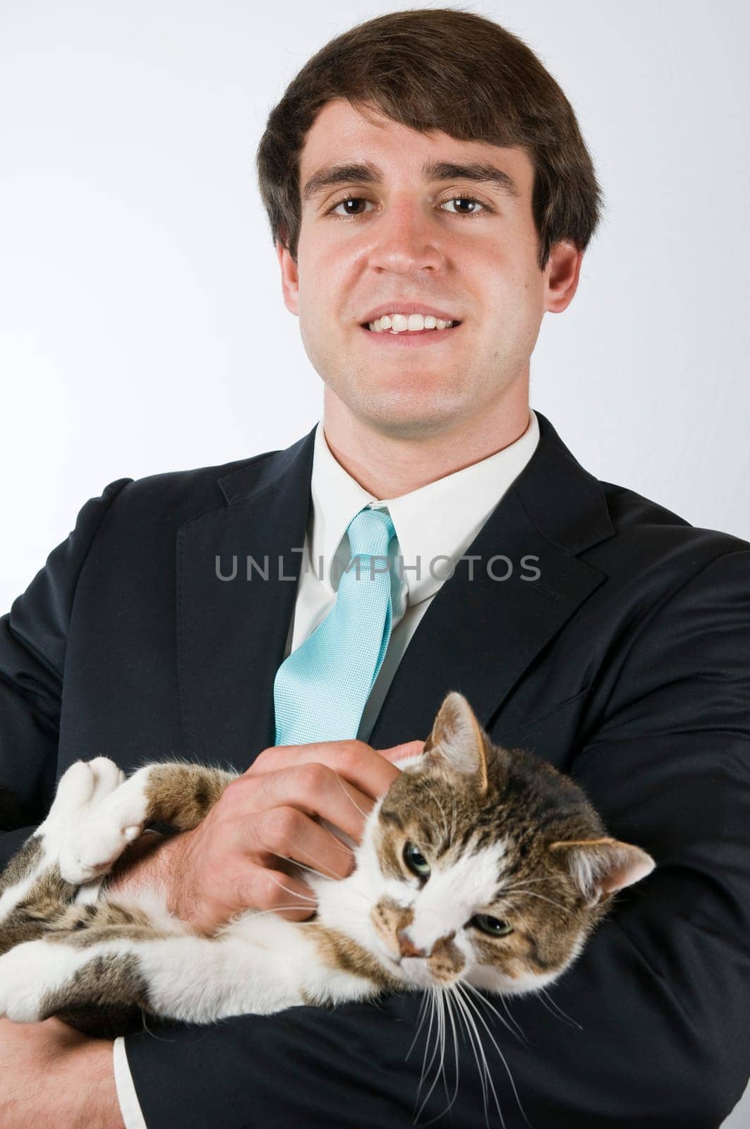 Upper body portrait of a man in a black suit with a wiggling cat in his arms smiling into the camera