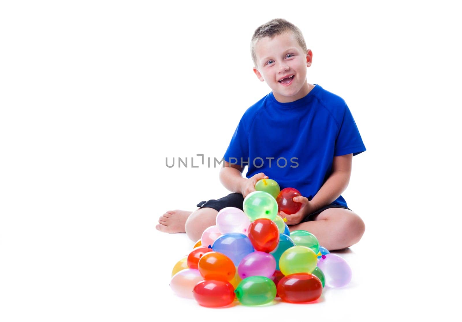Boy with a pile of water balloons isolated on white background