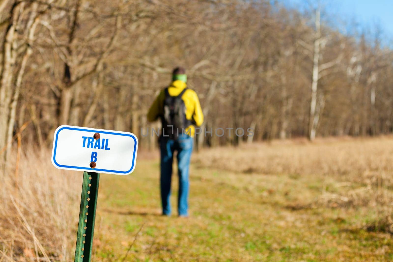 Image of a hiker on a trail with focus on the trail marker
