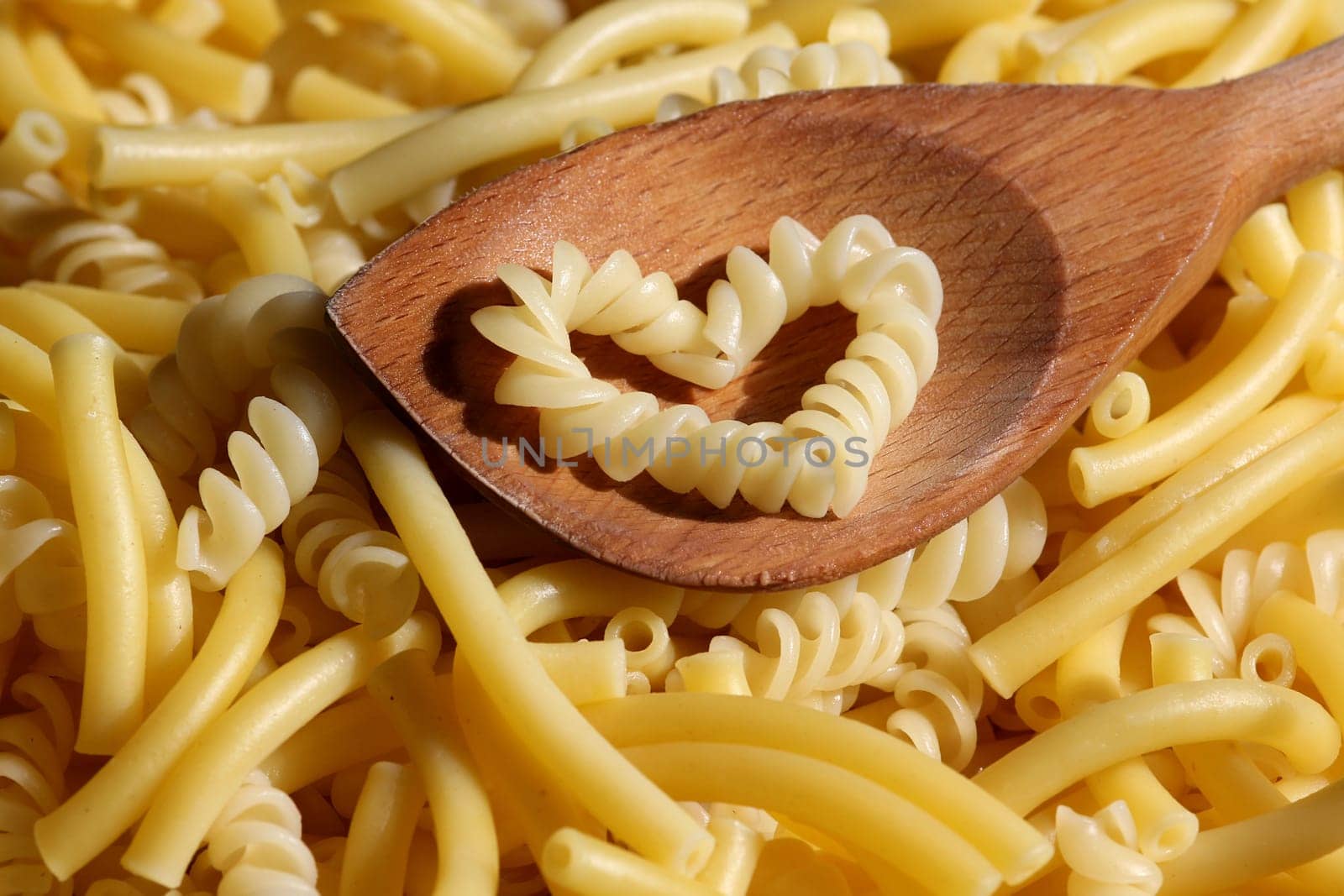 Pasta with heart on wooden spoon