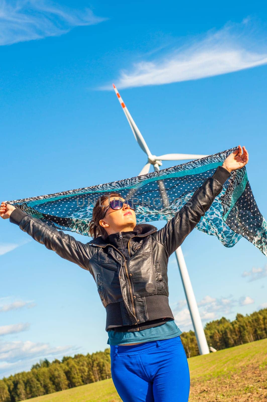 An image of girl holding canvas-cape and windturbine in background