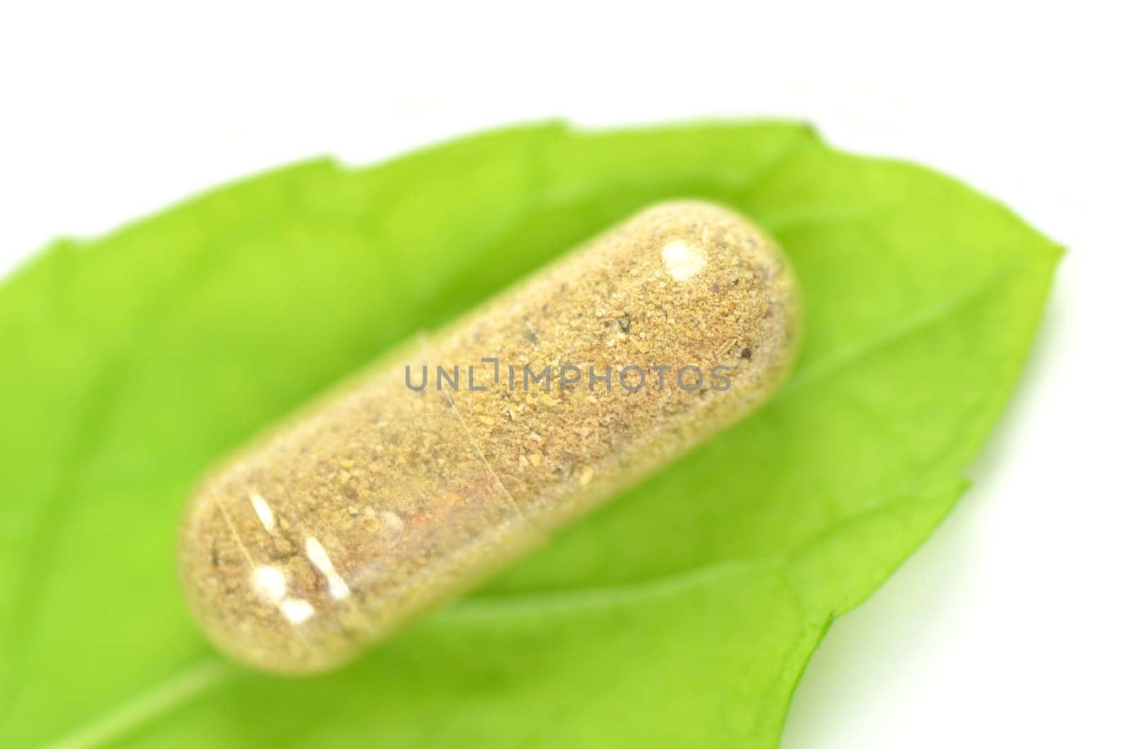 closeup of herbal capsules on mint leaf isolated on white background