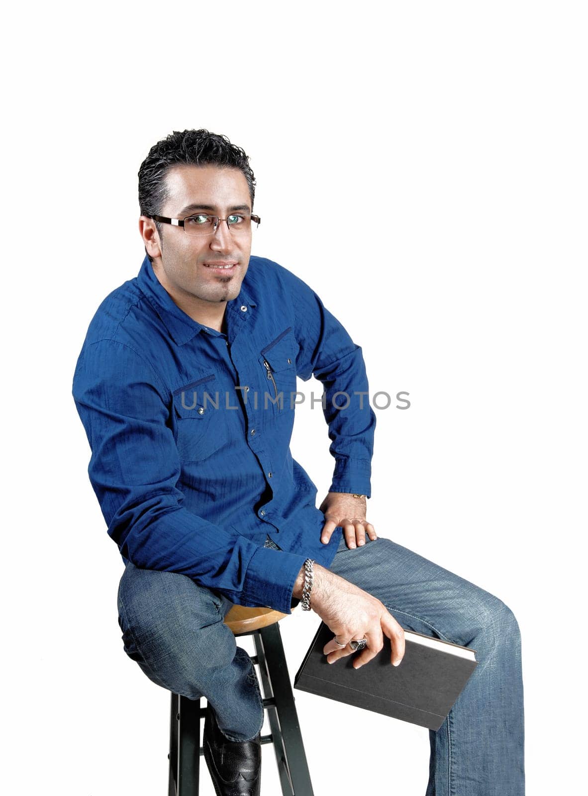 A young man in a blue white shirt sitting whit a book in his hand.looking into the camera, smiling, for white background..