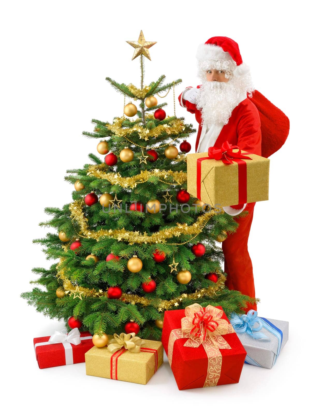 Santa Claus stands next to the Christmas tree and presents a gift box