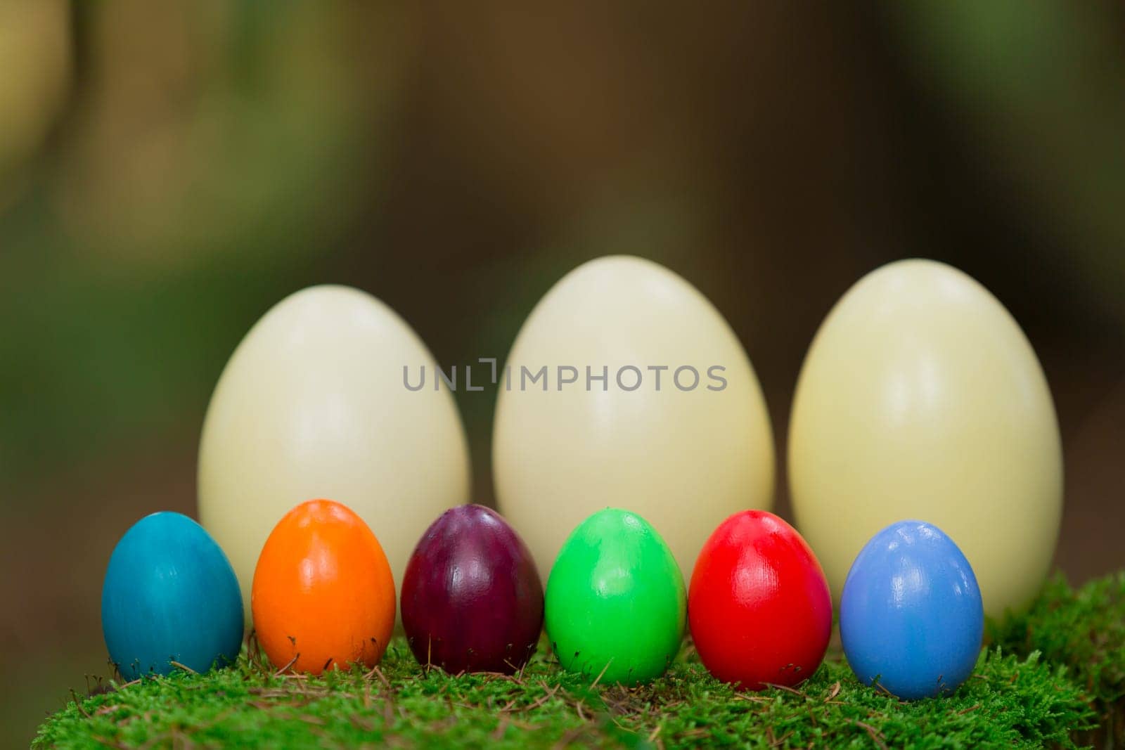 Colorful Easter eggs and three Nandu eggs on a tree stump