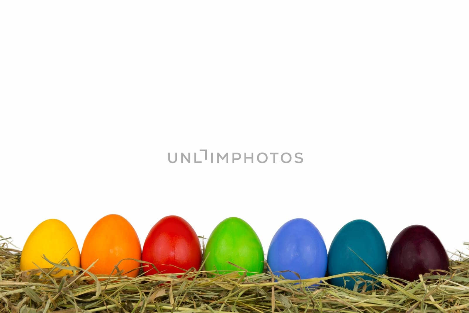 Colorful Easter eggs in the hay at the bottom of the picture