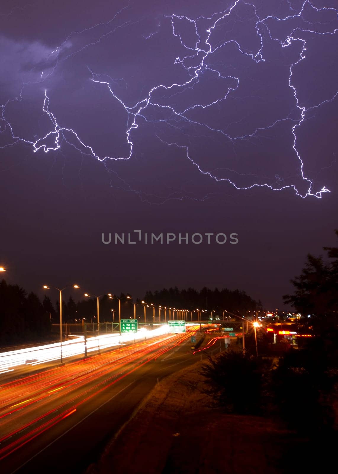 Batch of lightning over a busy highway at night