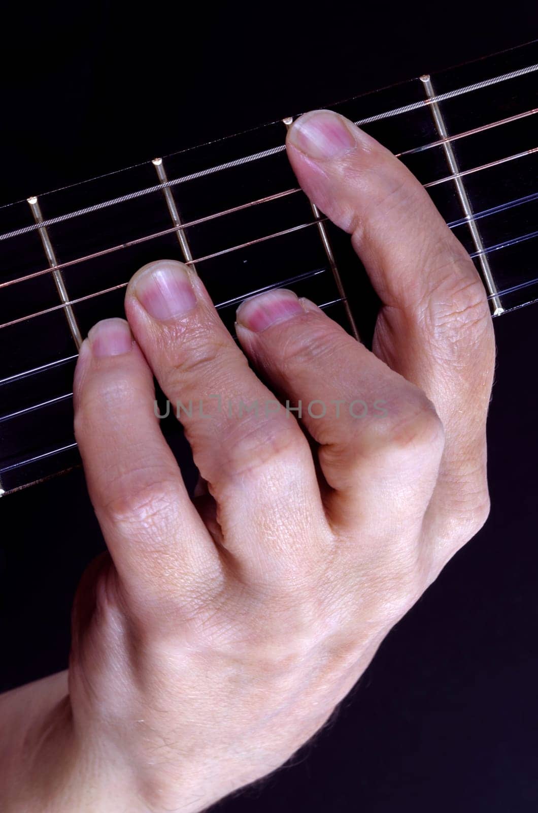 Close up of guitarist holding down a chord on the fretboard