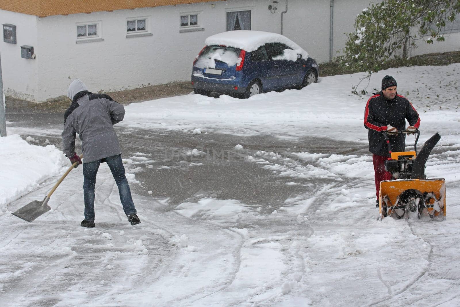Two men clear the street in winter