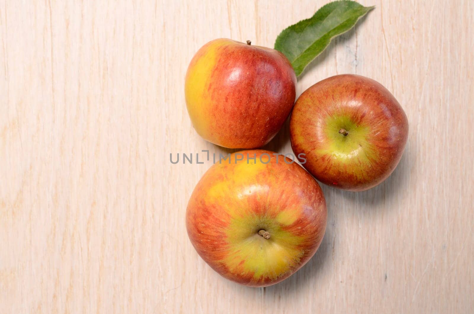 Three fresh apples on a wooden table with space for text