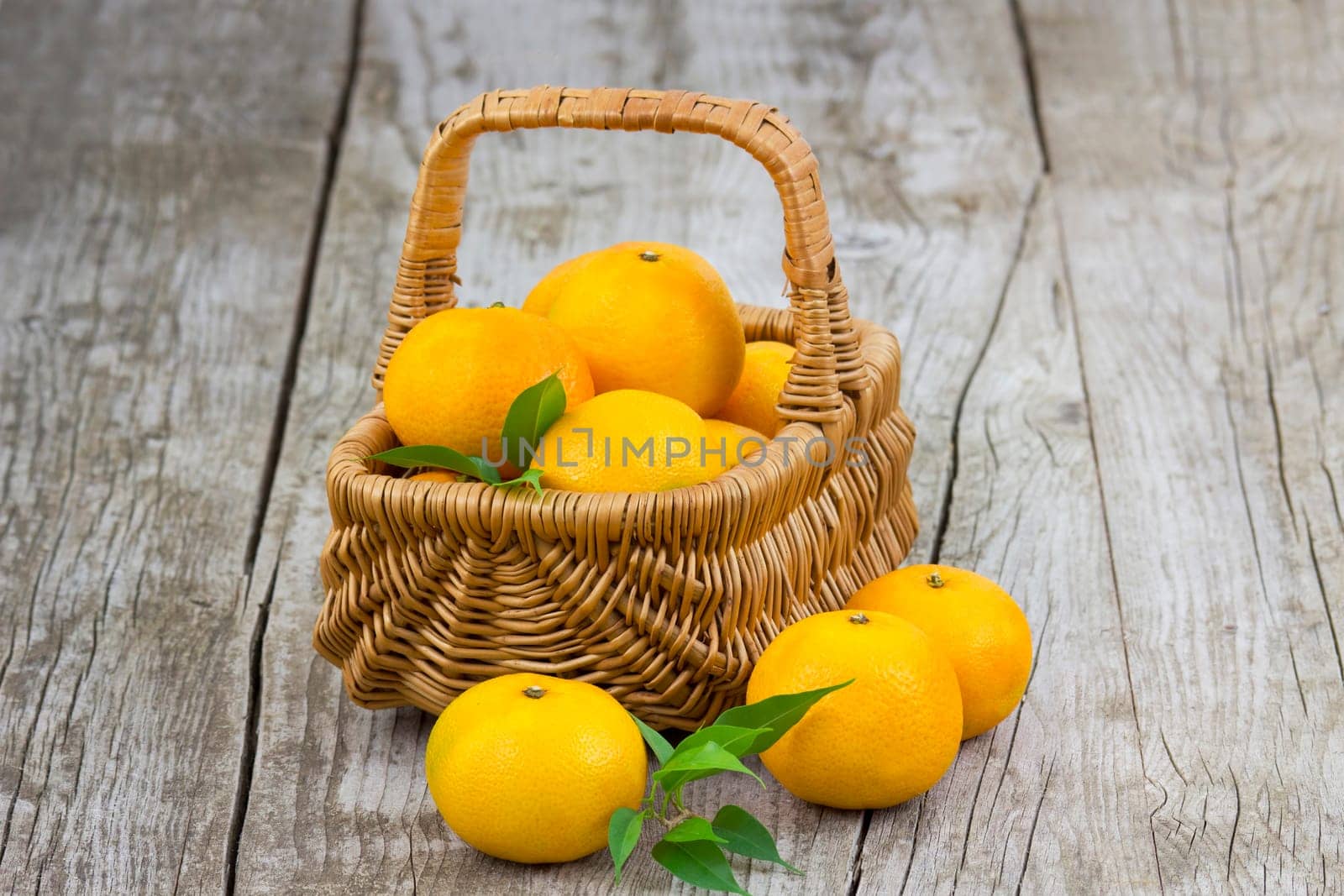 fresh tangerines in a basket on old wooden background