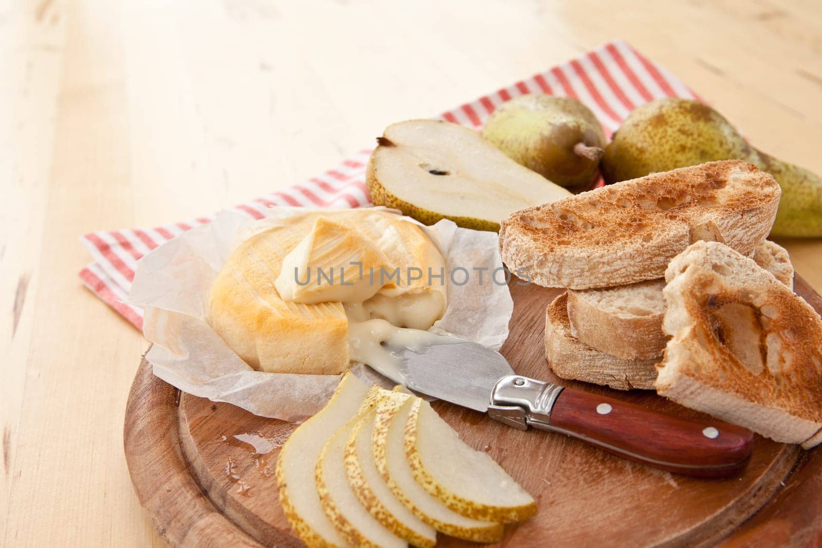 Caese,bread and fresh pears on cutting board