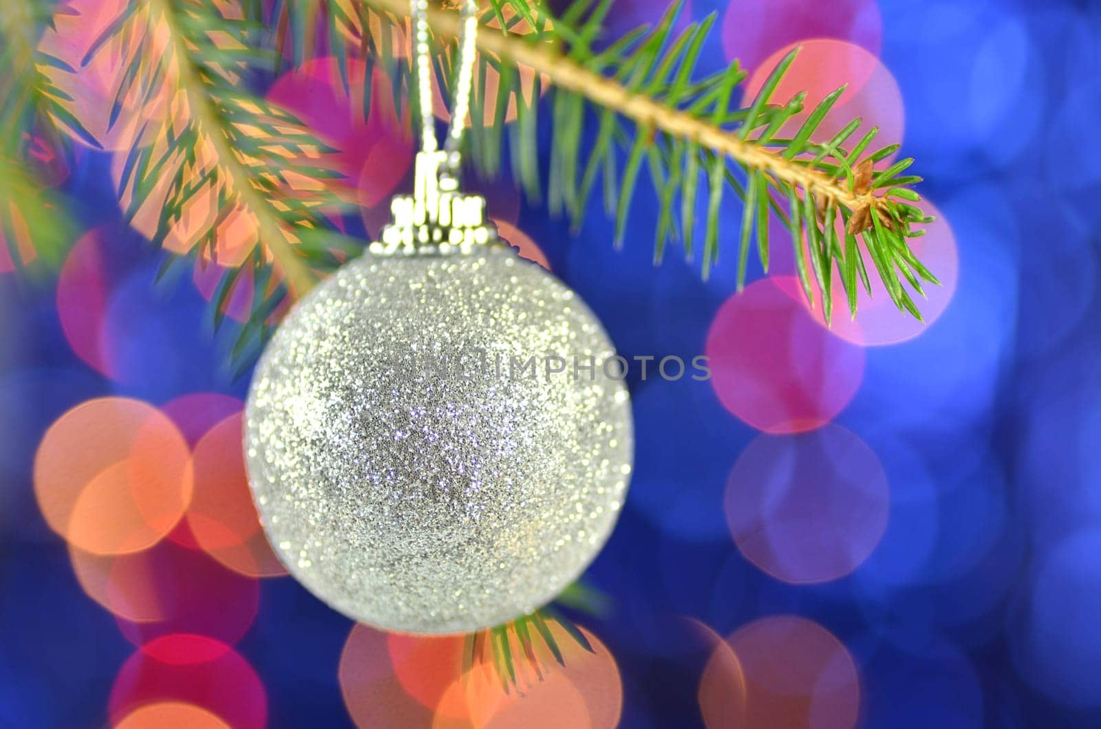 christmas decoration, golden Christmas ball hanging on spruce twig against bokeh background