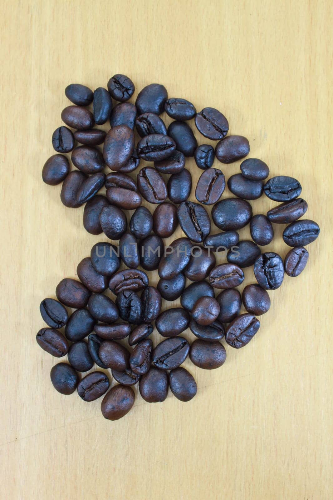 heart image made up of coffee beans on wood background
