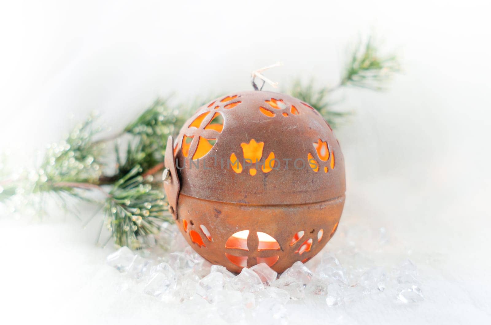 Spherical Christmas candle on ice with fir branch in the background