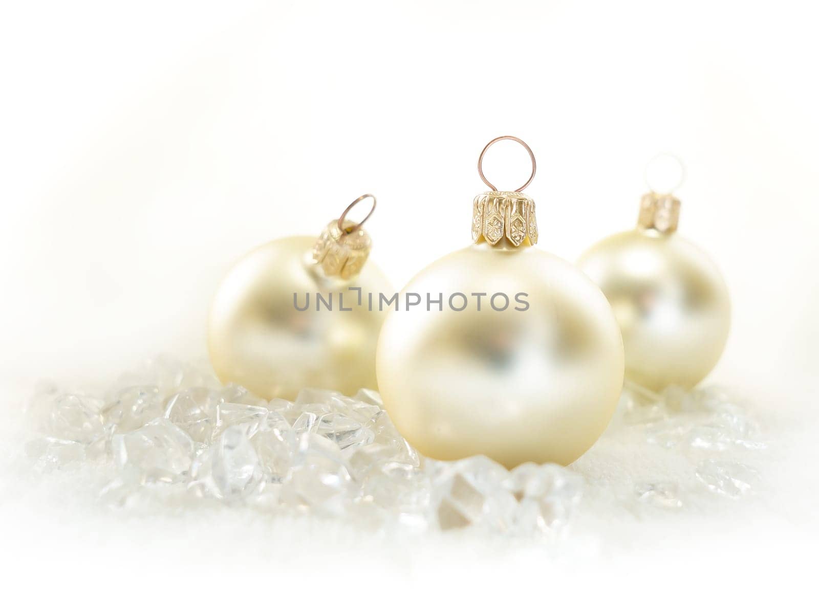 Three golden Christmas baubles on ice