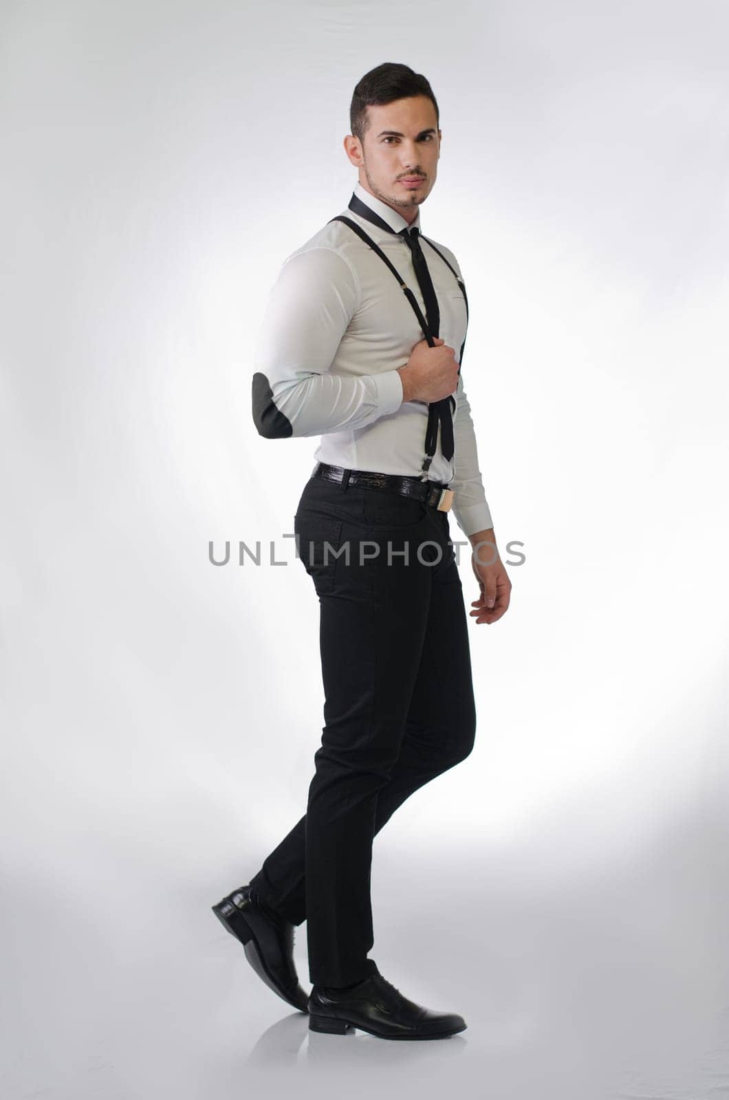 Full body shot of elegant and stylish young man on light background, profile standing